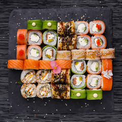 Japanese sushi set. Various types of roles on plate over stone background. Top view.