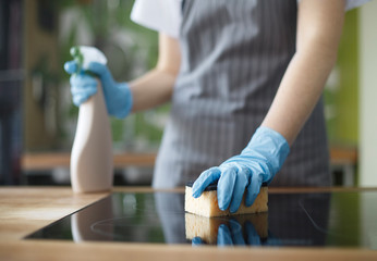 Unrecognizable woman cleaning kitchen in gloves with disinfecting spray