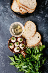 Baked snails with garlic butter and fresh herbs in a frying pan, selective focus