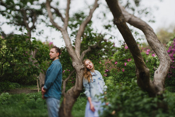 Romantic and happy caucasian couple in casual clothes hugging on the background of beautiful blooming lilac. Love, relationships, romance, happiness concept. Man and woman walking outdoors together.