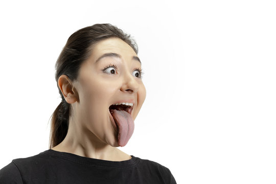Smiling girl opening her mouth and showing the long big giant tongue isolated on white background. Looks shocked, attracted, wondered and astonished. Copyspace for ad. Human emotions, marketing.