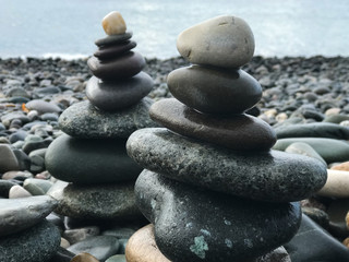 two pyramids of sea smooth stones of different shades lie on the coast
