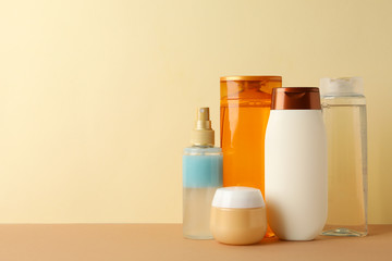 Blank cosmetic bottles on beige background, space for text