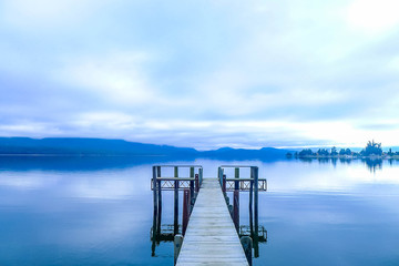 wooden pier at a lake in a dark cloudy atmosphere