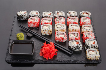 Japanese restaurant, sushi roll on black slate. Set for two with ginger and wasabi on a dark background.