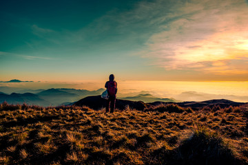 An adult mountainer standing at the peak of Mt. Pulag enjoying the breathtaking view of sea of clouds during sunrise