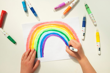 Top view of a boy colouring in an image of a rainbow