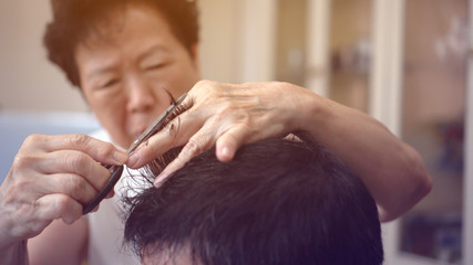Fototapeta premium Asian family mother do barber haircut for son at home during quarantine time