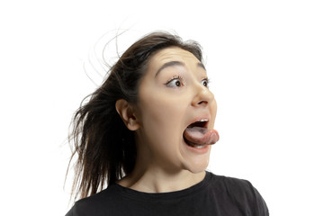 Smiling girl opening her mouth and showing the long big giant tongue isolated on white background. Looks shocked, attracted, wondered and astonished. Copyspace for ad. Human emotions, marketing.