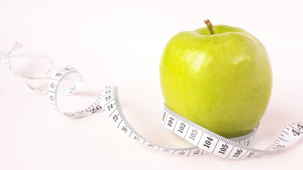Fresh green fruits wrapped in a measuring tape.Concept of the goal to lose weight,the goal of diet.