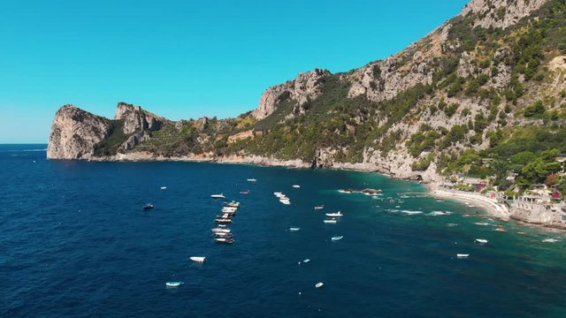 Aerial view of coastline of the village of Nerano. Private and wild beaches of Italy. Turquoise, blue surface of the water. Vacation and travel concept. Boats on raid in bay. Copy space. Summer day