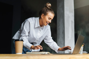 Distance learning. Beautiful smiling woman in white shirt works in front of laptop. A student prepares seminar