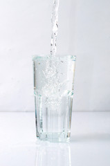 Splashing liquid, water is pouring into a glass