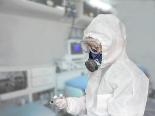 防護服を身に着け治療室で注射器を手にする男性