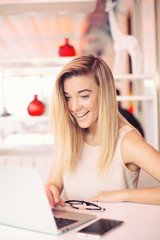 a beautiful happy  young smiling businesswoman is working  on a laptop in a cosy cafe  in the morning