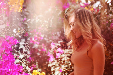 a young beautiful girl is standing near the flowers and smiling