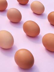 Chicken eggs on a pink background with sunlight and shadows