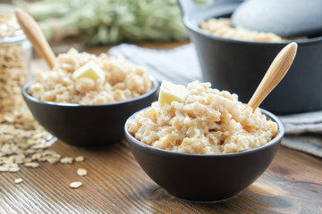 Two bowls of healthy oatmeal porridge on wooden kitchen table.
