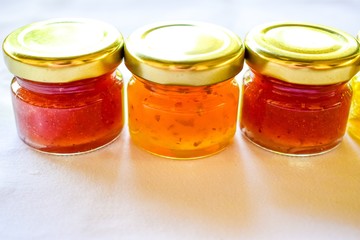 pineapple, orange and strawberry jams in the small glass bottle
