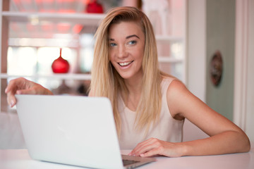 a young smiling businesswoman is working  on a laptop in a cosy cafe 