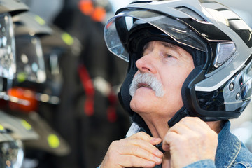 senior man fastening crash helmet