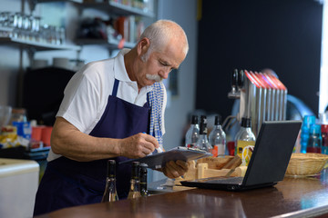 Fototapeta na wymiar senior waiter with digital tablet standing at bar