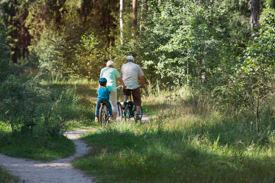 active senior couple with little granddaughter riding bikes in nature