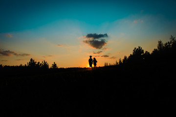 Silhouette of happy boy and girl run at sunset