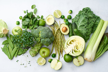 Table with healthy vegetarian meal ingredients. Raw food concept. A variety of organic fruits and vegetables with avocado. Vegan menu, broccoli, peas, lime, green beans, kale and apple..