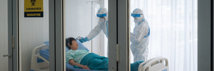 doctor and nurse in personal protective equipment or ppe treating the asian woman patient with...