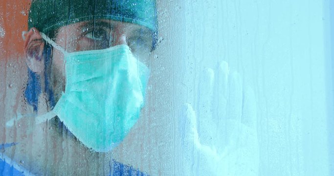 Coronavirus, medico disperato guarda fuori dalla finestra durante la pioggia