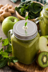 Healthy green smoothie in jar on wooden table.	