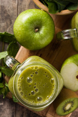 Healthy green smoothie in jar on wooden table. Top view