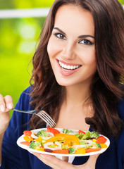 Portrait picture of happy smiling young brunette woman with vegetarian vegetable salad