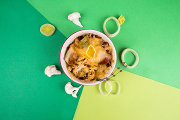 Obraz na płótnie Canvas Cauliflower gratin with leek, chicken breast and cheese over on green background.