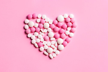 Beautiful heart symbol made from pills medicine health care concept. Flat lay top view picture on the pink background