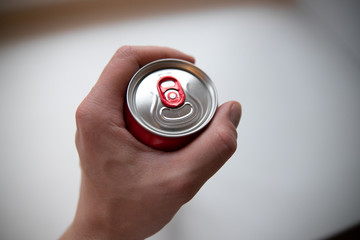 hand holding a close aluminum can of drink. View from above.