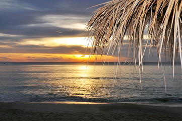 Closeup view of straw umbrella at sunset on the beach