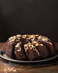 Sweet Homemade Dark Chocolate Bundt Cake with almonds over dark background, copy space. Selective focus. Ready to Eat.