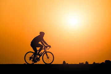Obraz premium Silhouette man cycling on sunset background