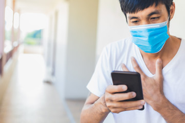 Man asian wear surgical mask hold smartphone search news covid 19 for stop covid 19 virus covid-19 or corona protected Help protect For social distancing world and people treatment method stop virus