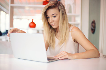 a beautiful happy  young smiling businesswoman is working  on a laptop in a cosy cafe  in the morning