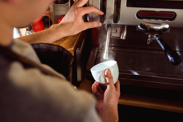 Details of barista preparing fresh espresso on industrial brewing machinery.