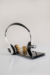 close up of a phone and coins stacks with headphones