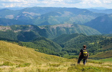 Fototapeta na wymiar Hiker standing on top of a mountain and enjoying mountains landscape. Travel concept vacations hiking with backpack in mountains