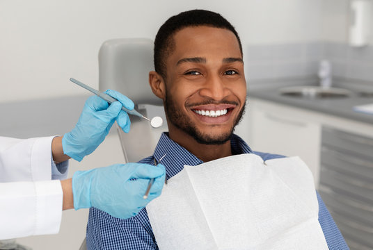 Cheerful african guy in dentist chair, visiting modern clinic