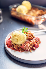 Home cooked Rhubarb and Strawberry crumble from oatmeal and nuts topping and with vanilla ice cream scoops