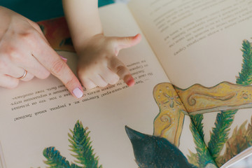 Hands of a woman and child reading a children's book
