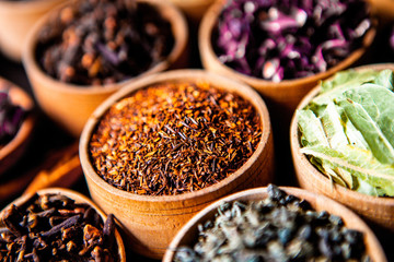 Various dried tea leaves in wooden bowl. Dried herbs tea leaves close up. Different dry herbs and flowers for making healthy tea background.