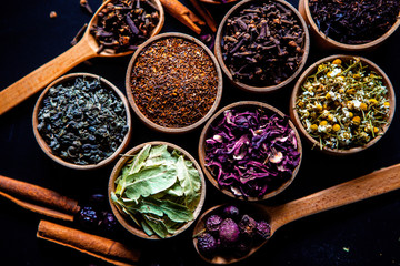 Various dried tea leaves in wooden bowl. Dried herbs tea leaves close up. Different dry herbs and flowers for making healthy tea background.